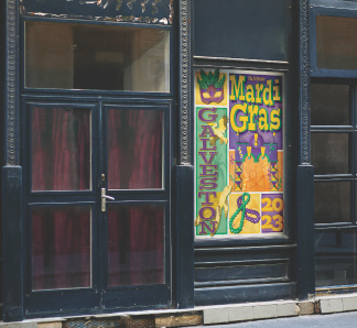 Galveston Mardi Gras poster with green, purple, yellow, and orange accent colors. There is a pelican and sea turtle next to the words Galveston with beads a mask and the Galveston Mardi gras archway.